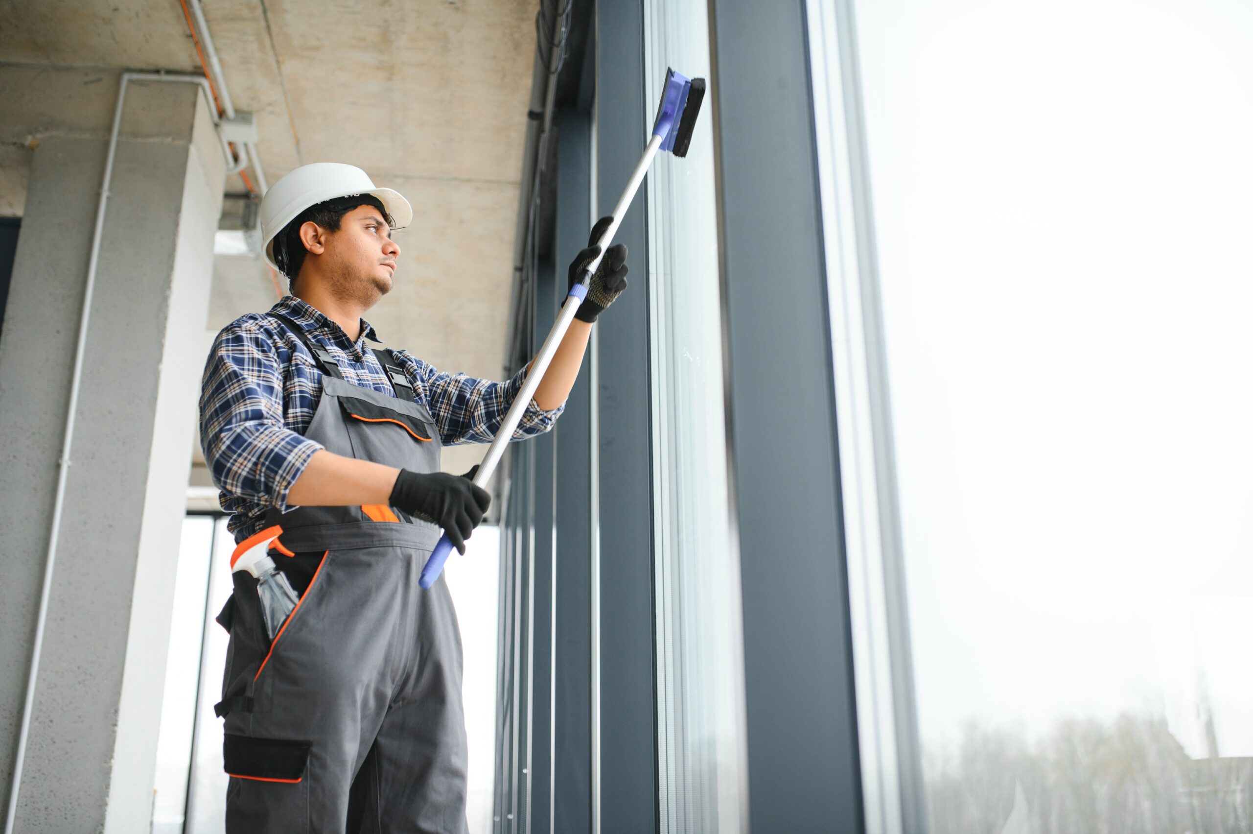 Male professional cleaning service worker cleans the windows and shop windows of a store with special equipment