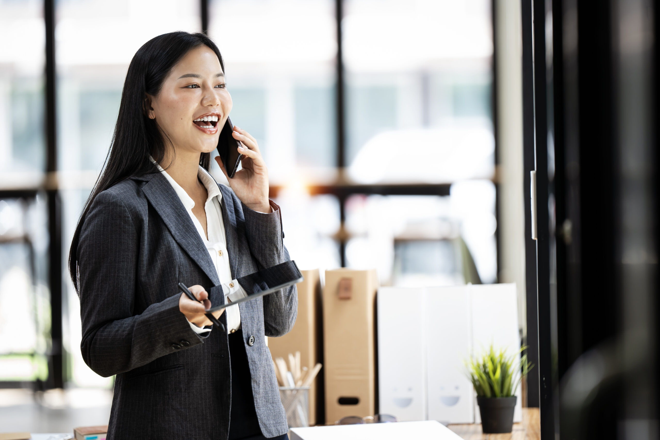 Confident Asian woman with a smile standing holding notepad and